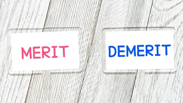 木目の床に置かれた「MERIT」と「DEMERIT」と書かれた2枚のカード