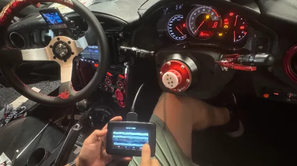 GT86の運転席でリモートツールを手に持ちデータを書き換えている様子